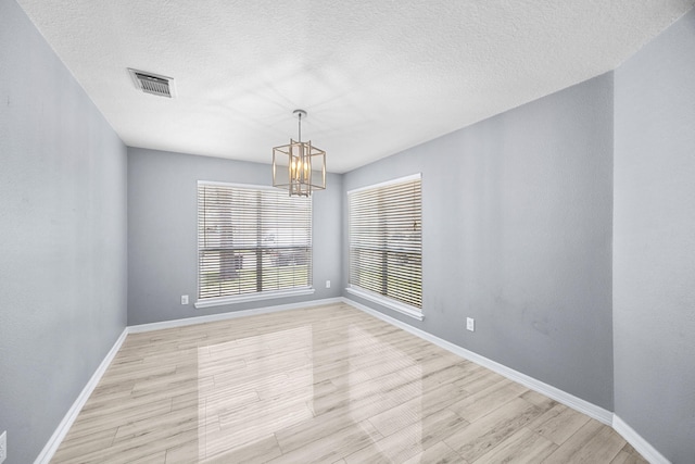 612 Hartman Dr, Baytown, TX 77521 - empty room with a chandelier, light wood-type flooring, baseboards, and a textured ceiling