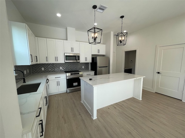 6412 Highland Pine Ln, Houston, TX 77091 - kitchen with appliances with stainless steel finishes, a sink, a kitchen island, backsplash, and light wood finished floors