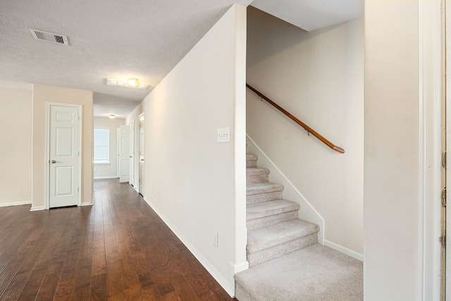 6352 Austinville Dr, Katy, TX 77449 - hallway featuring dark wood-style floors, baseboards, stairs, and a textured ceiling