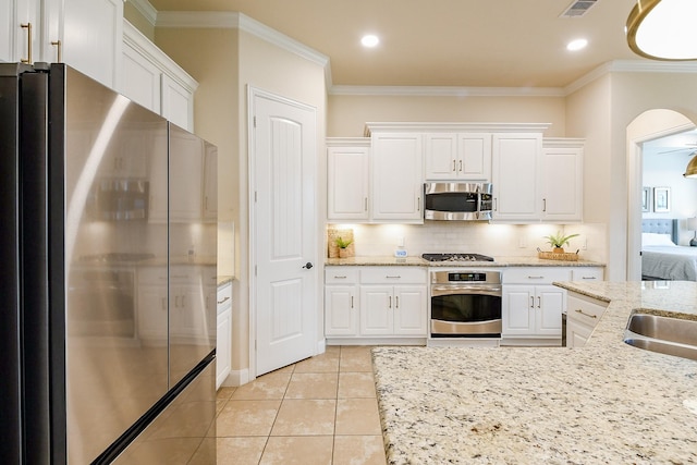 2800 Spencer Ct, Pearland, TX 77089 - kitchen featuring appliances with stainless steel finishes, crown molding, white cabinets, arched walkways, and tasteful backsplash