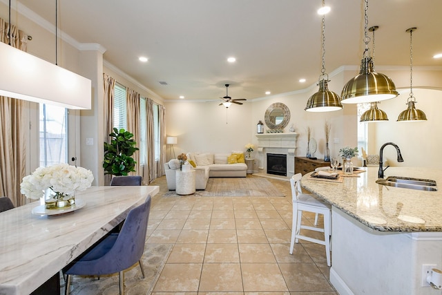 2800 Spencer Ct, Pearland, TX 77089 - kitchen with a sink, crown molding, a fireplace, a ceiling fan, and light tile patterned floors
