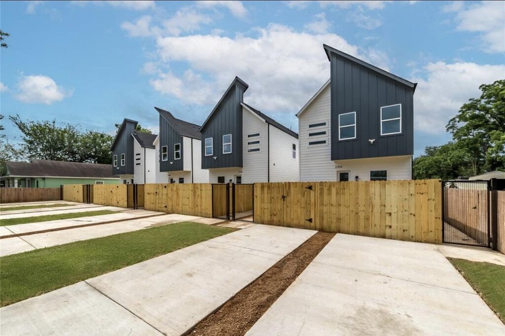 2704 Bostic St, Houston, TX 77093 - view of side of property with board and batten siding, a gate, a fenced front yard, and a residential view
