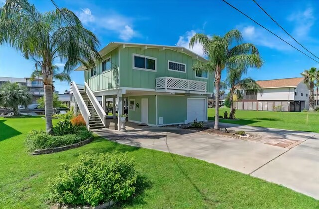 22201 Matagorda Dr, Galveston, TX 77554 - back of property featuring board and batten siding, a lawn, driveway, stairway, and an attached garage