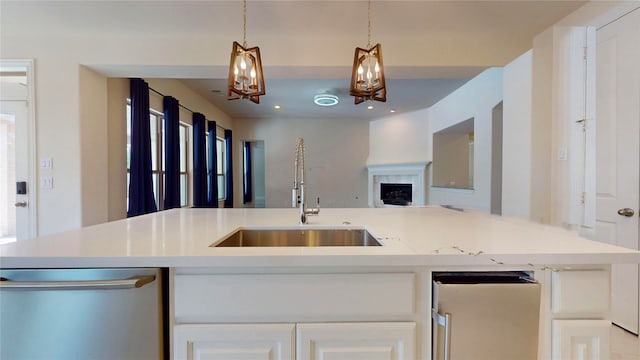 10255 S Goshawk Trl, Conroe, TX 77385 - kitchen with stainless steel dishwasher, a sink, open floor plan, light countertops, and hanging light fixtures