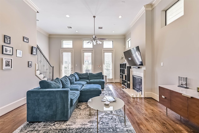 2425 Polk St, Houston, TX 77003 - living room featuring wood finished floors, a glass covered fireplace, ornamental molding, ceiling fan, and baseboards