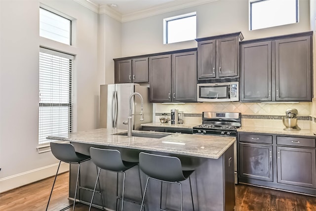 2425 Polk St, Houston, TX 77003 - kitchen with appliances with stainless steel finishes, a sink, an island with sink, a kitchen breakfast bar, and decorative backsplash
