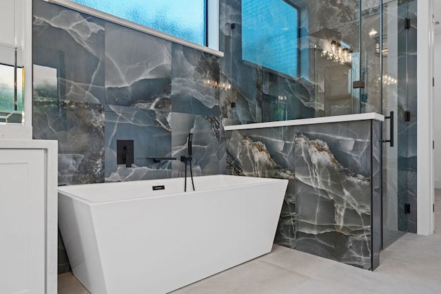 91 Lake Sterling Gate Dr, Spring, TX 77379 - bathroom featuring tile walls, a soaking tub, a marble finish shower, and concrete flooring