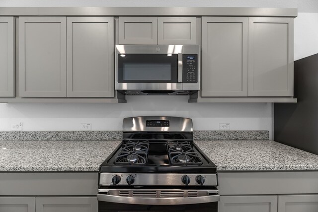 1662 Portia Ln, Conroe, TX 77301 - kitchen with stainless steel appliances, gray cabinetry, and light stone countertops