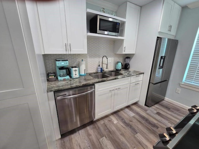1513 47th St, Galveston, TX 77551 - kitchen with stainless steel appliances, a sink, light stone counters, and white cabinets