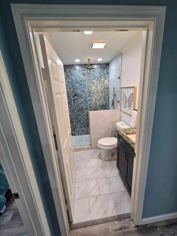 1513 47th St, Galveston, TX 77551 - full bathroom featuring marble look tiles, a shower stall, toilet, and vanity