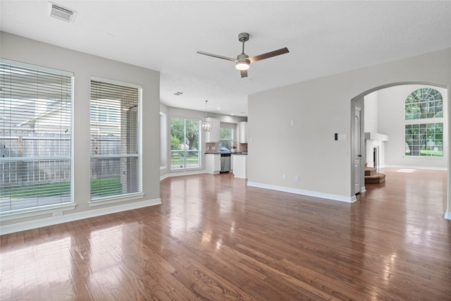 19203 Allview Ln, Houston, TX 77094 - unfurnished living room with ceiling fan, arched walkways, wood finished floors, baseboards, and a fireplace with raised hearth
