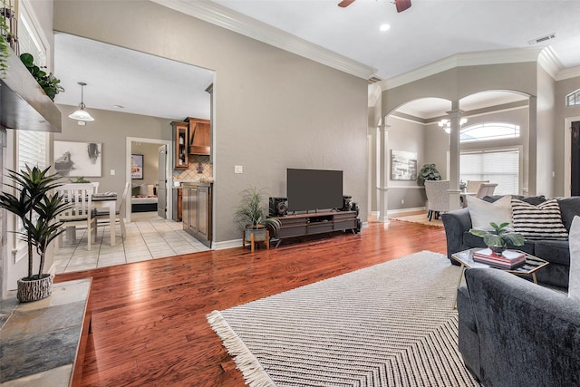 2707 Colony Creek Dr, Bryan, TX 77808 - living room featuring ornate columns, arched walkways, ceiling fan, light wood-style floors, and ornamental molding