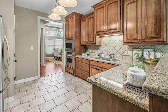 2707 Colony Creek Dr, Bryan, TX 77808 - kitchen with stainless steel appliances, a sink, baseboards, backsplash, and brown cabinets