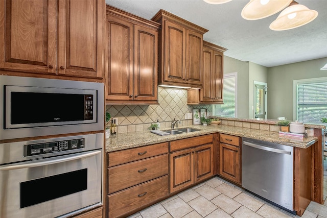 2707 Colony Creek Dr, Bryan, TX 77808 - kitchen with appliances with stainless steel finishes, tasteful backsplash, a peninsula, brown cabinets, and a textured ceiling