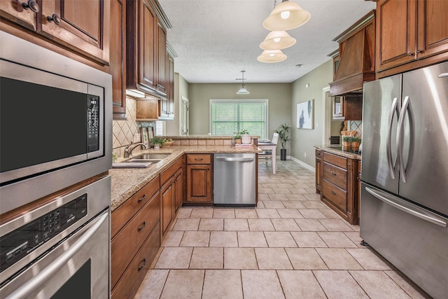 2707 Colony Creek Dr, Bryan, TX 77808 - kitchen featuring appliances with stainless steel finishes, backsplash, a peninsula, a sink, and brown cabinets