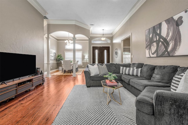 2707 Colony Creek Dr, Bryan, TX 77808 - living area featuring ornate columns, arched walkways, crown molding, wood finished floors, and a chandelier