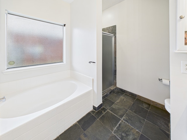 1035 Turnberry Park Ln, Spring, TX 77373 - bathroom with a garden tub, a shower stall, stone finish flooring, baseboards, and toilet