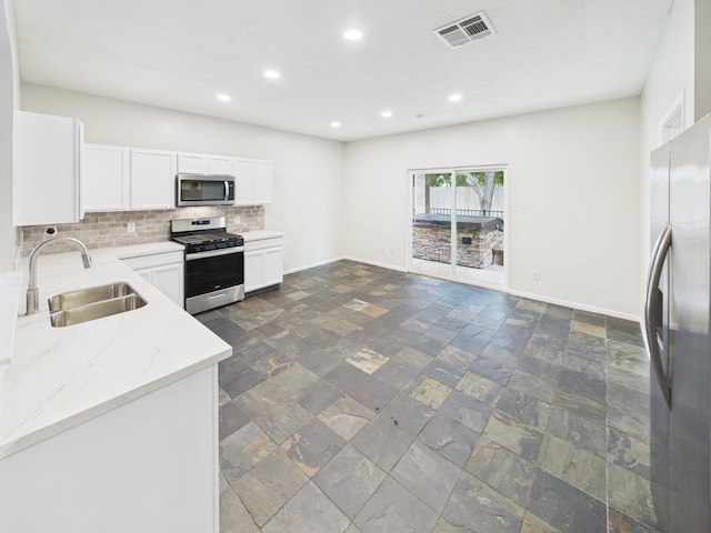 1035 Turnberry Park Ln, Spring, TX 77373 - kitchen with appliances with stainless steel finishes, a sink, stone tile flooring, tasteful backsplash, and baseboards