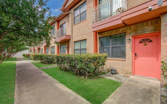9400 Bellaire Blvd Unit 112, Houston, TX 77036 - doorway to property with brick siding, a balcony, and a lawn