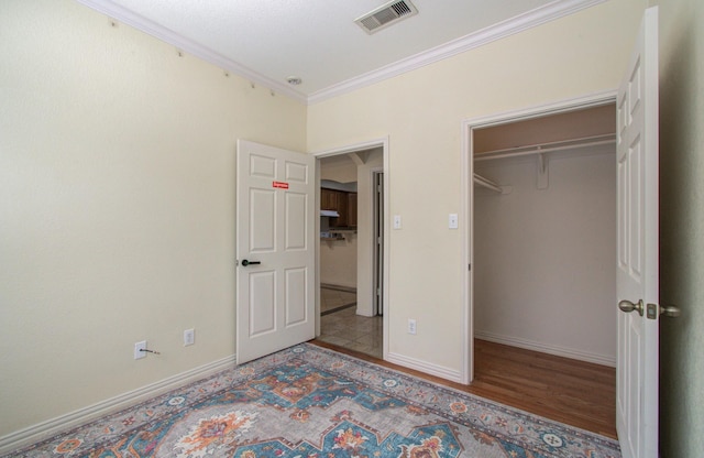 9400 Bellaire Blvd Unit 112, Houston, TX 77036 - unfurnished bedroom featuring crown molding, baseboards, wood finished floors, a walk in closet, and a closet
