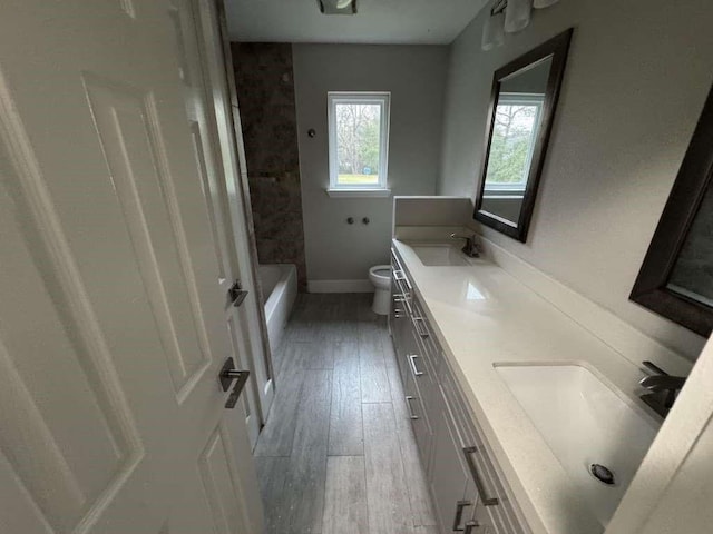 529 Brandon Rd, Conroe, TX 77302 - full bath with double vanity, toilet, wood finished floors, baseboards, and washtub / shower combination