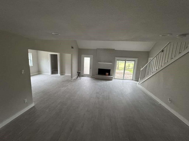 529 Brandon Rd, Conroe, TX 77302 - unfurnished living room with vaulted ceiling, baseboards, wood finished floors, stairway, and a textured ceiling