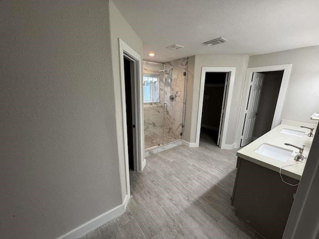 529 Brandon Rd, Conroe, TX 77302 - full bathroom with a marble finish shower, wood finished floors, double vanity, a textured ceiling, and baseboards