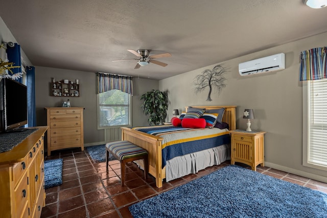 22 Indian Creek Loop, Kerrville, TX 78028 - bedroom featuring a wall unit AC, baseboards, a textured ceiling, a ceiling fan, and dark tile patterned floors
