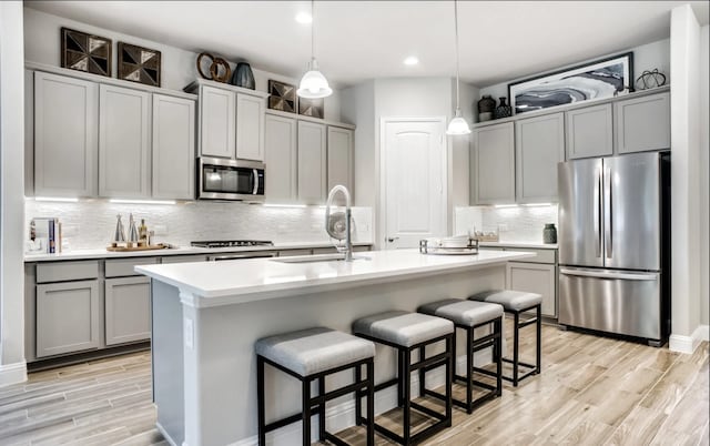 2227 Inglenook Grove Dr, Katy, TX 77493 - kitchen with appliances with stainless steel finishes, a sink, gray cabinets, light wood-style flooring, and tasteful backsplash