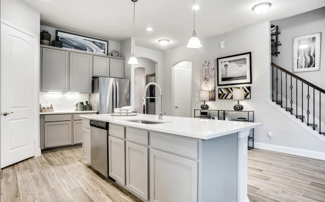 2227 Inglenook Grove Dr, Katy, TX 77493 - kitchen with a sink, appliances with stainless steel finishes, gray cabinets, arched walkways, and light wood-style flooring