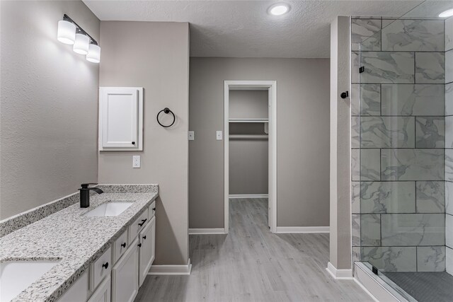 3626 Liles Ln, Humble, TX 77396 - bathroom with wood finished floors, double vanity, tiled shower, baseboards, and a textured ceiling