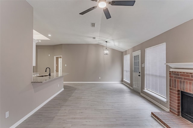 3626 Liles Ln, Humble, TX 77396 - unfurnished living room featuring a sink, a brick fireplace, light wood-style flooring, a ceiling fan, and baseboards