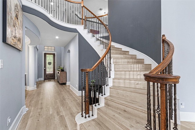 16714 Radiant Lilac Trl, Cypress, TX 77433 - entrance foyer featuring arched walkways, baseboards, wood finished floors, stairs, and decorative columns