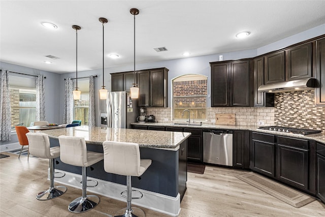 16714 Radiant Lilac Trl, Cypress, TX 77433 - kitchen with appliances with stainless steel finishes, a sink, under cabinet range hood, a center island, and light wood-type flooring