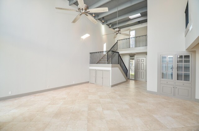 6 River Hollow Ln, Houston, TX 77027 - unfurnished living room with ceiling fan, a towering ceiling, stairs, beam ceiling, and baseboards