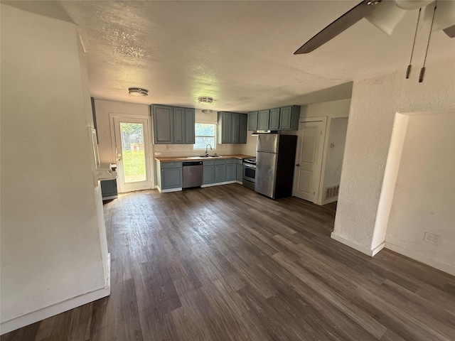 445 W Vaughan St, Bertram, TX 78605 - kitchen with stainless steel appliances, a sink, gray cabinets, dark wood-style floors, and baseboards