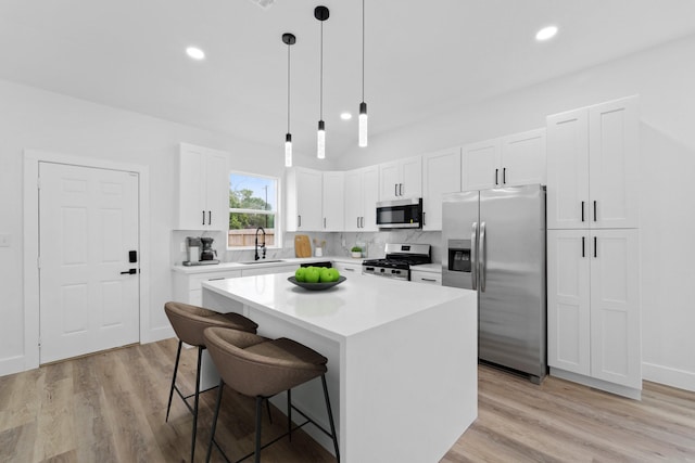 821 Empire St, El Campo, TX 77437 - kitchen featuring stainless steel appliances, a sink, a kitchen bar, decorative backsplash, and recessed lighting