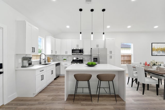 821 Empire St, El Campo, TX 77437 - kitchen featuring appliances with stainless steel finishes, a sink, a breakfast bar area, backsplash, and a center island