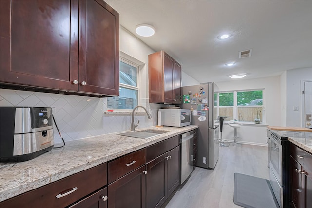12602 Westleigh Dr, Houston, TX 77077 - kitchen featuring stainless steel appliances, a sink, light wood-type flooring, backsplash, and light stone countertops