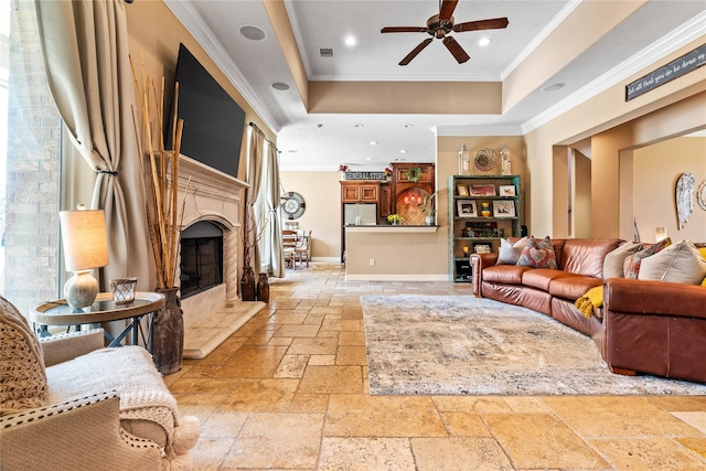 2509 Creektrail Ln, Richmond, TX 77406 - living area featuring stone tile flooring, a raised ceiling, ornamental molding, a ceiling fan, and a premium fireplace