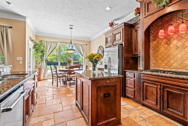 2509 Creektrail Ln, Richmond, TX 77406 - kitchen featuring appliances with stainless steel finishes, stone tile floors, a kitchen island, dark stone countertops, and ornamental molding