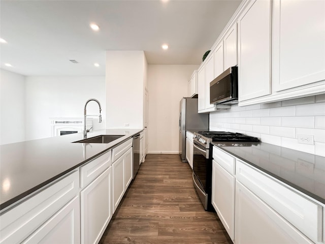 5667 Foggy Vine Ct, Fulshear, TX 77441 - kitchen featuring appliances with stainless steel finishes, a sink, dark wood-style flooring, dark countertops, and recessed lighting