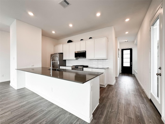 5667 Foggy Vine Ct, Fulshear, TX 77441 - kitchen featuring stainless steel appliances, a sink, dark wood finished floors, decorative backsplash, and dark countertops