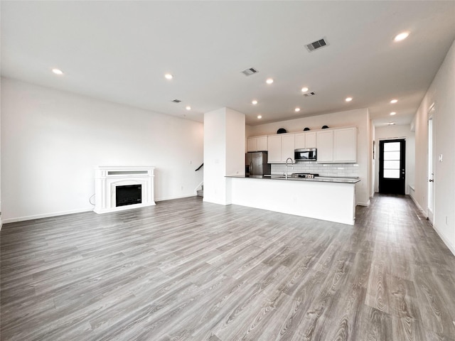 5667 Foggy Vine Ct, Fulshear, TX 77441 - unfurnished living room with light wood finished floors, a sink, stairs, recessed lighting, and baseboards