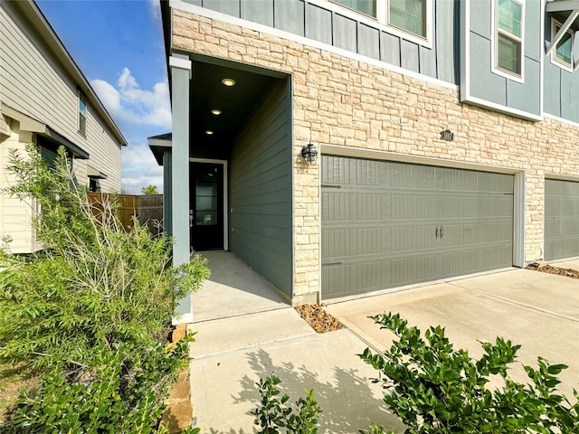 5667 Foggy Vine Ct, Fulshear, TX 77441 - doorway to property with a garage, stone siding, board and batten siding, and driveway