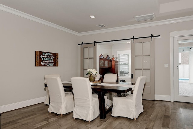 2205 Salt Grass Trl, Conroe, TX 77384 - dining area featuring a barn door, crown molding, wood finished floors, plenty of natural light, and baseboards