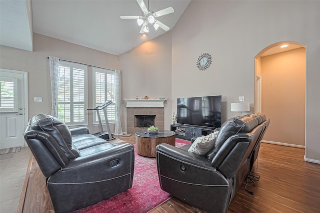 24623 Forest Hiker Ct, Katy, TX 77493 - living room featuring arched walkways, ceiling fan, wood finished floors, a fireplace, and high vaulted ceiling