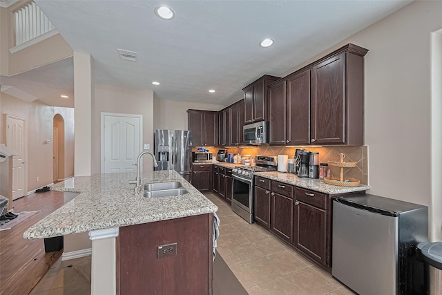 24623 Forest Hiker Ct, Katy, TX 77493 - kitchen featuring appliances with stainless steel finishes, a sink, a breakfast bar area, dark brown cabinets, and recessed lighting