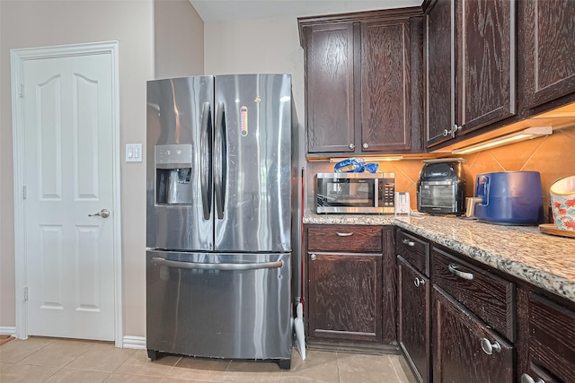 24623 Forest Hiker Ct, Katy, TX 77493 - kitchen with appliances with stainless steel finishes, light tile patterned flooring, dark brown cabinets, tasteful backsplash, and light stone counters