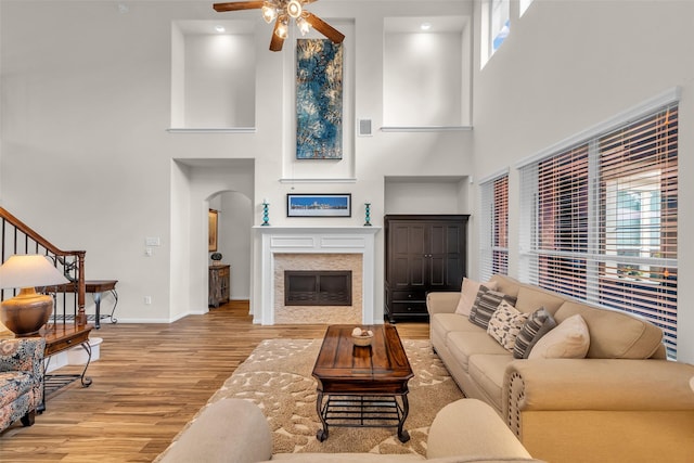 6406 Pine Reserve Dr, Spring, TX 77389 - living area featuring a towering ceiling, ceiling fan, wood finished floors, arched walkways, and a glass covered fireplace